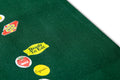Green MACK tote bag featuring colorful fruit sticker design, casual carryall with sturdy handles and vibrant print.
