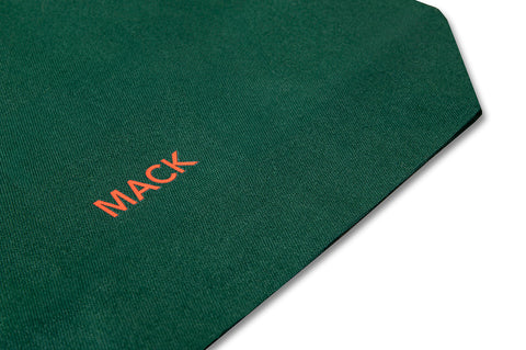 Green tote bag with colorful fruit stickers from MACK, featuring a casual design and sturdy handles.